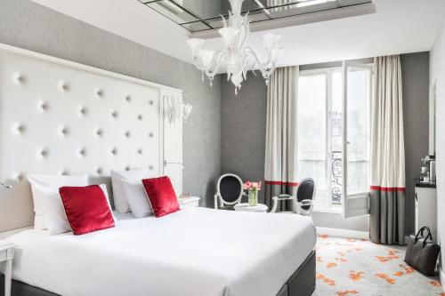 a bedroom with a large white bed with red pillows at Maison Albar - Le Diamond in Paris