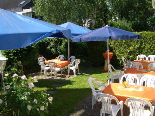 a group of tables and chairs with blue umbrellas at Hotel Roemerstein in Mainz