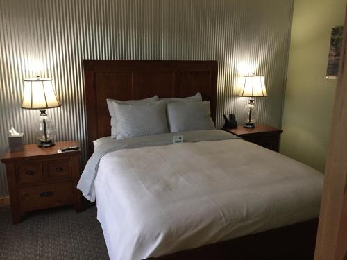 a bedroom with a large white bed with two lamps at Roam Inn in Munising