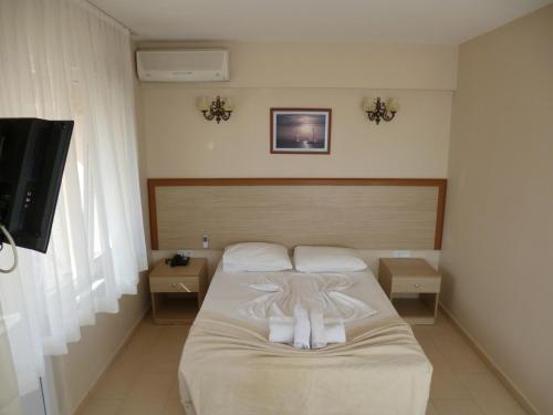 a bedroom with a bed with white sheets and a flat screen tv at Istanbul Yildiz Hotel in Marmaraereglisi