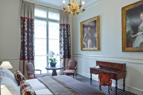a bedroom with a bed and a table and a piano at Hôtel Mansart - Esprit de France in Paris