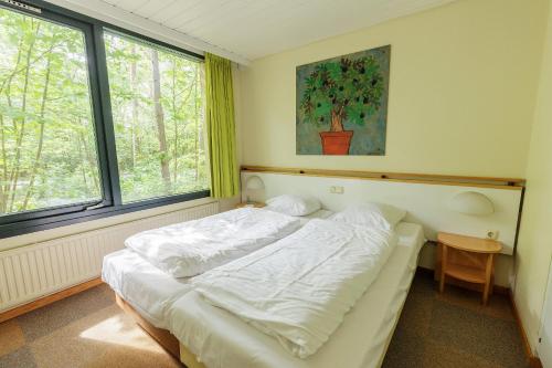 a bedroom with a white bed in front of a window at Center Parcs Bispinger Lüneburger Heide in Bispingen