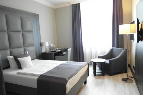 a bedroom with a bed and a desk and a chair at Hotel Chemnitzer Hof in Chemnitz