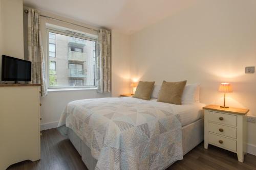 a white bedroom with a bed and a window at Citystay - Mill Park Apartments in Cambridge