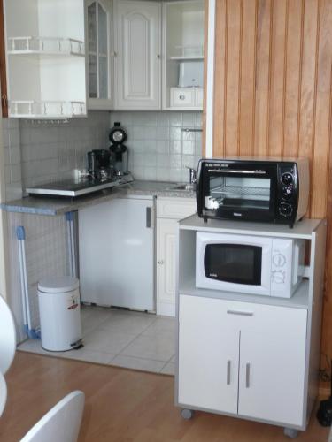 une cuisine avec un four micro-ondes au-dessus d'un comptoir dans l'établissement Regard Sur La Baie, à Saint-Valery-sur-Somme