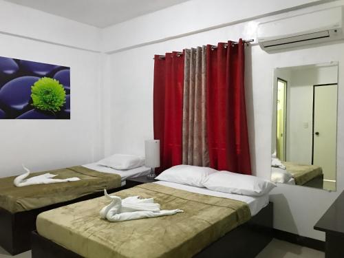 a bedroom with two beds with red curtains at 4C's Tourist Lodge in Puerto Princesa City