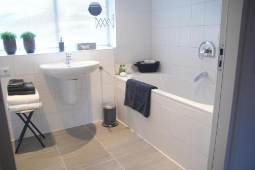 ein Badezimmer mit einem Waschbecken, einer Badewanne und einem Waschbecken in der Unterkunft Bed and Breakfast de Verwennerij in Ermelo