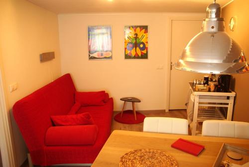 a living room with a red couch and a table at Bed and Breakfast de Verwennerij in Ermelo