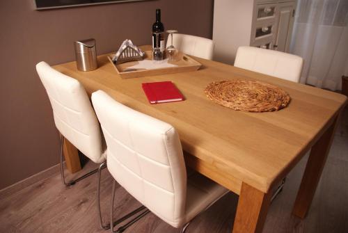a wooden table with white chairs and a bottle of wine at Bed and Breakfast de Verwennerij in Ermelo