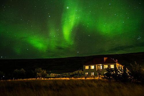 an image of the aurora dancing in the sky over a house at Guesthouse Storu-Laugar in Laugar