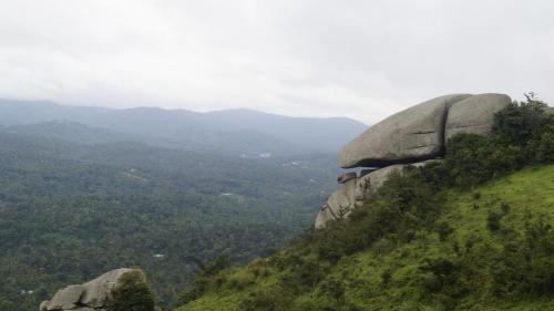 a rock on top of a hill with a valley at Skyrock Inn in Kattappana