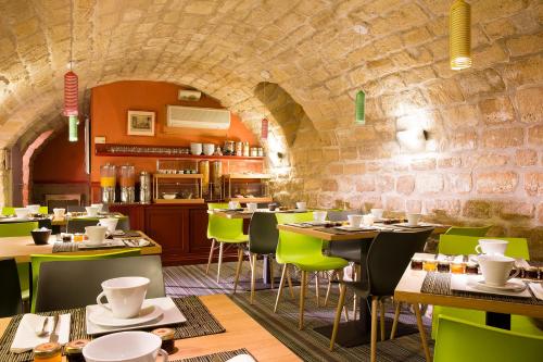 un restaurant avec des tables et des chaises et un mur en pierre dans l'établissement Apollon Montparnasse, à Paris