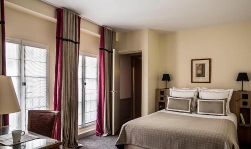 a bedroom with a large bed with red curtains at Hôtel de la Place du Louvre - Esprit de France in Paris