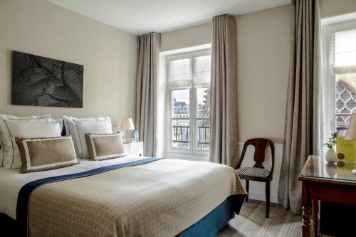 a bedroom with a bed and a chair and a window at Hôtel de la Place du Louvre - Esprit de France in Paris
