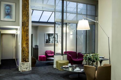 un salon avec une table et des chaises violettes dans l'établissement Hôtel de la Place du Louvre - Esprit de France, à Paris