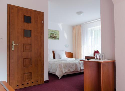 a bedroom with a bed and a wooden door at Hotel Nidzki in Ruciane-Nida