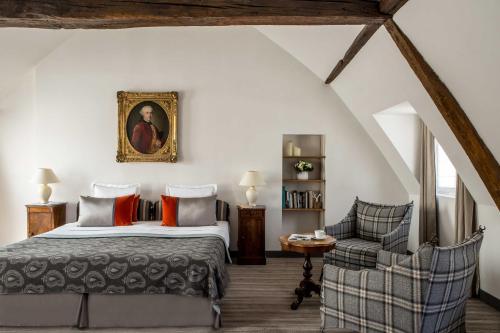 a bedroom with a king sized bed and a chair at Hôtel d'Orsay - Esprit de France in Paris