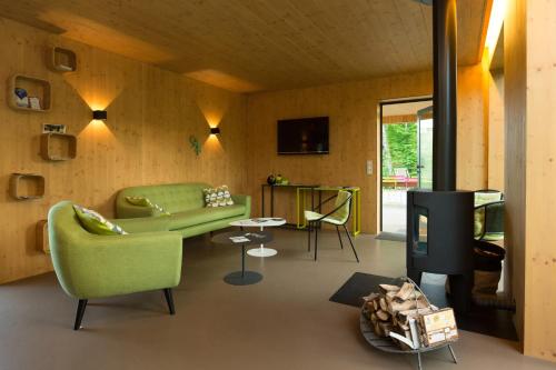 - un salon avec un canapé vert et une cheminée dans l'établissement Les Cabanes de Salagnac, à Meyrignac-lʼÉglise