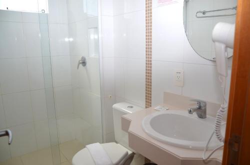 uma casa de banho com um WC, um chuveiro e um lavatório. em Luisa Palace Hotel em Florianópolis