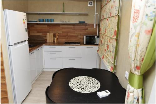 a small kitchen with a table and a white refrigerator at Apartment on Pichugina in Karagandy