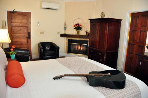 a bedroom with a guitar on a bed with a fireplace at The Eagle Inn in Santa Barbara