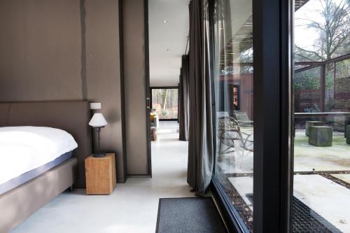 a bedroom with a bed and a glass door with a window at Stalen Boshuis in Oosterhout