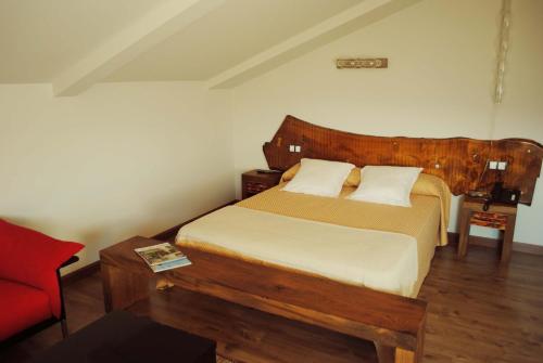 a bedroom with a wooden bed and a red chair at El Lacayo de Sestiello in Grado