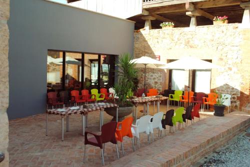 a row of tables and chairs with colorful chairs at El Lacayo de Sestiello in Grado