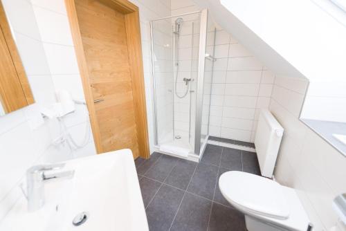 a white bathroom with a toilet and a shower at Hotel Rhönhof in Hünfeld