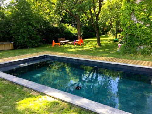 a swimming pool in a yard with chairs and trees at La Sapinière de Vittel in Vittel