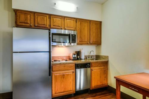a kitchen with a stainless steel refrigerator and wooden cabinets at Hyatt House Chicago Schaumburg in Schaumburg