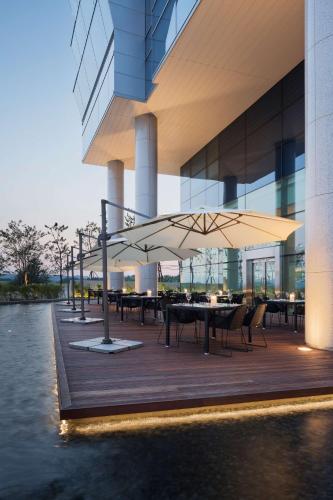 a building with tables and chairs and a large umbrella at Grand Hyatt Incheon in Incheon