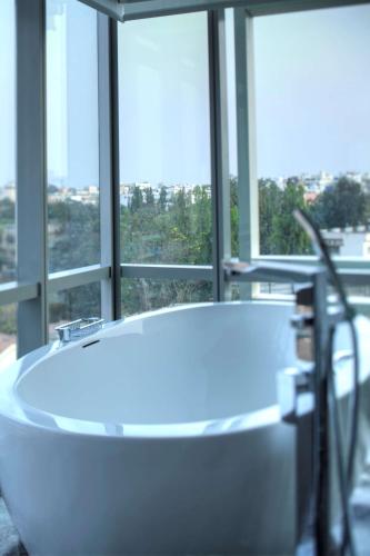 a white bath tub in a room with windows at Park Hyatt Hotel and Residences, Hyderabad in Hyderabad