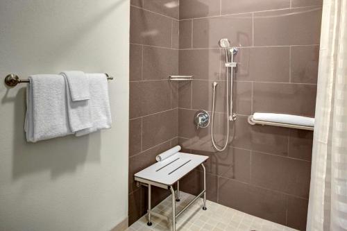 a bathroom with a shower with a stool in it at HYATT House Shelton in Shelton