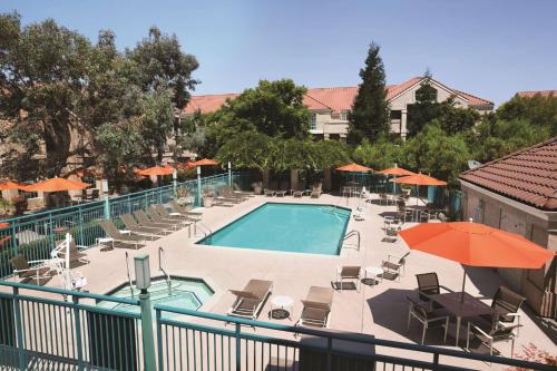 a swimming pool with chairs and umbrellas on a balcony at Hyatt House Pleasanton in Pleasanton