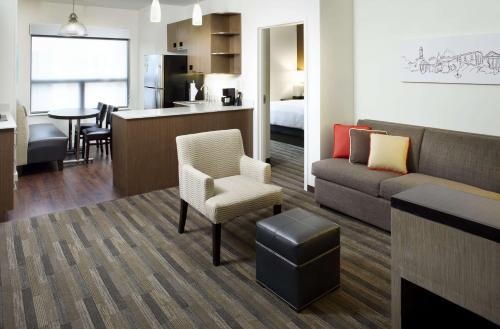 a living room with a couch and a chair and a kitchen at HYATT House Pittsburgh-South Side in Pittsburgh