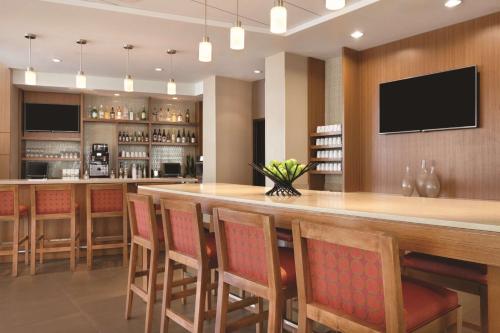 a kitchen with a large bar with chairs and a television at Hyatt Place at Anaheim Resort / Convention Center in Anaheim