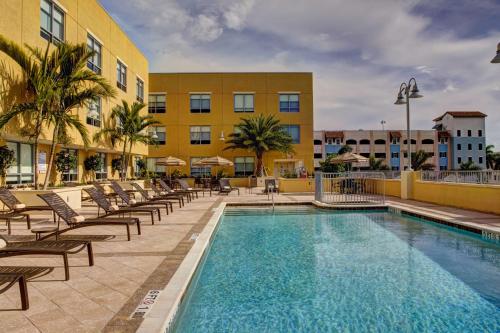 a beach with a pool, chairs, and a pool table at Hyatt Place Delray Beach in Delray Beach
