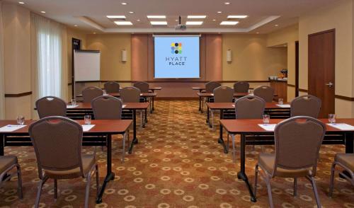 a conference room with tables and chairs and a screen at Hyatt Place Pensacola Airport in Pensacola