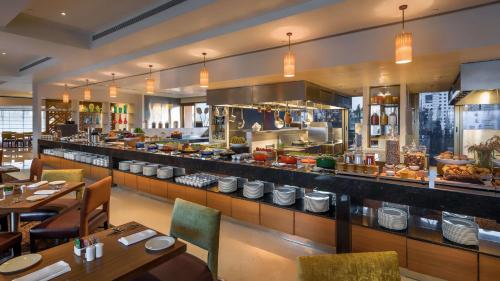 a restaurant with a buffet line with tables and chairs at Hyatt Place Pune Hinjawadi in Pune