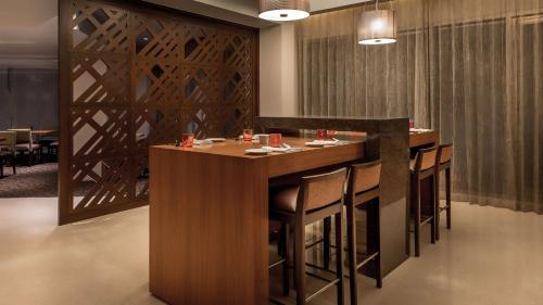 a bar in a restaurant with chairs around it at Hyatt Place Pune Hinjawadi in Pune