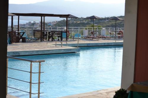 a swimming pool with chairs and tables and umbrellas at Mykali Hotel in Pythagoreio