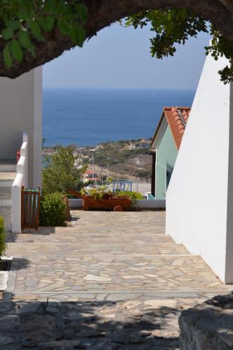 a stone walkway leading to a house with the ocean in the background at Mykali Hotel in Pythagoreio