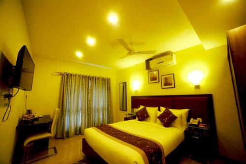 a bedroom with a large bed with yellow walls at D Breeze Suites in Devanahalli-Bangalore