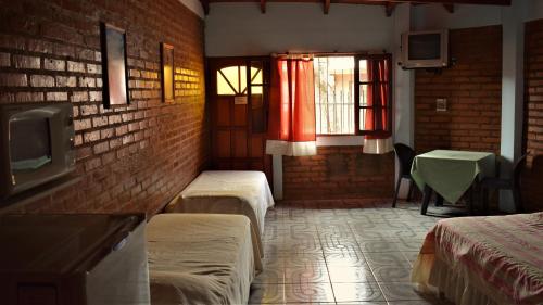 a room with two beds and a brick wall at marangatu apart hotel in Puerto Iguazú
