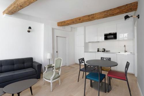 a living room with a couch and a table and chairs at L'Argenterie, Apparts de charme climatisé parking gratuit in Montpellier