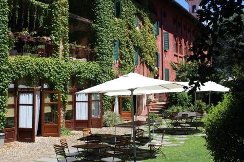 un patio con mesas, sillas y una sombrilla en Il Talucco B&B, en Valdengo