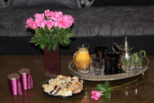 a table with a vase of flowers and a tray of food at Riad Terra Bahia in Marrakech