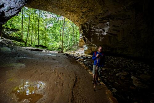 a man standing in front of a cave at Carter Caves State Resort Park in Olive Hill