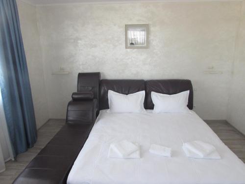 a white bed with two white pillows and a chair at La Marcu Pensiune in Tulcea